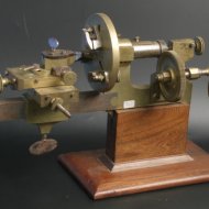 19th century brass and steel watchmaker lathe on wooden basement.