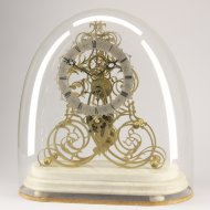 Antique english skeleton clock on white marble basement and under glass dome.